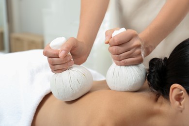 Photo of Young woman receiving herbal bag massage in spa salon, closeup