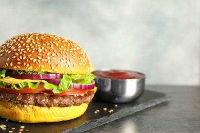 Photo of Burger with delicious patty and sauce on dark table against gray background, closeup