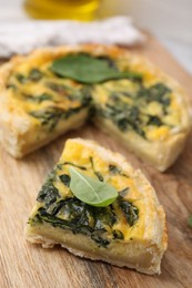 Photo of Piece of delicious pie with spinach on wooden board, closeup