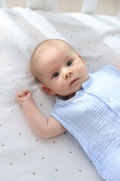 Photo of Cute little baby lying in crib at home, top view