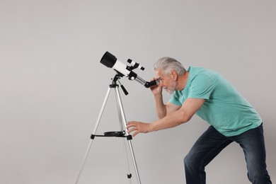 Photo of Senior astronomer with telescope on grey background