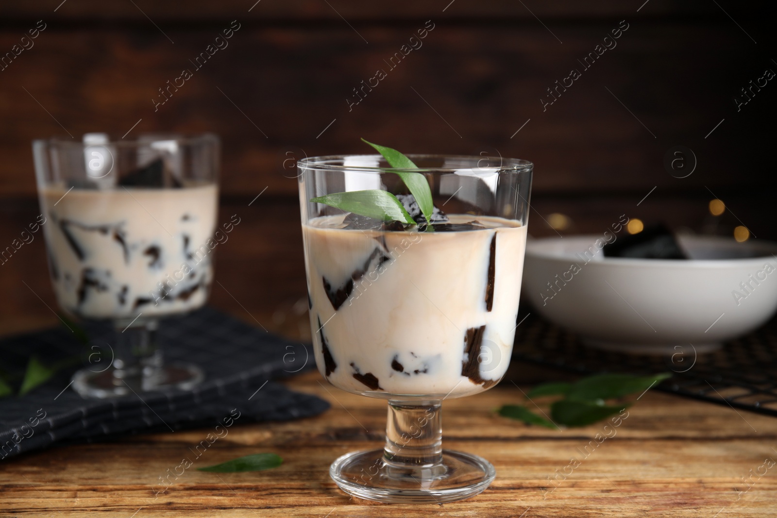 Photo of Glass of milk with grass jelly and green leaf on wooden table