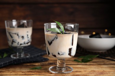 Photo of Glass of milk with grass jelly and green leaf on wooden table