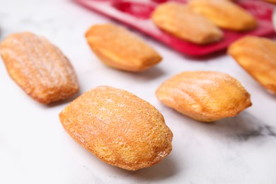 Delicious madeleine cookies and baking mold on white table, closeup