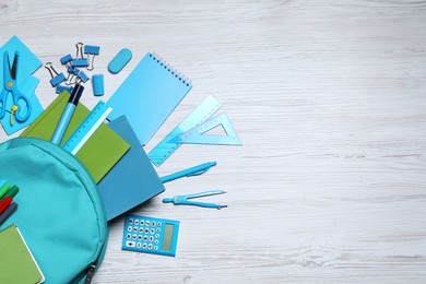 Photo of Flat lay composition with backpack and school stationery on white wooden background, space for text