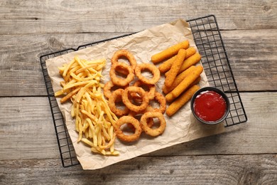 Photo of Tasty ketchup and different snacks on wooden table, top view