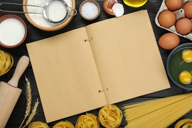 Photo of Blank recipe book and different ingredients on black wooden table, flat lay. Space for text