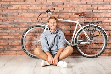 Photo of Handsome man with bicycle against brick wall