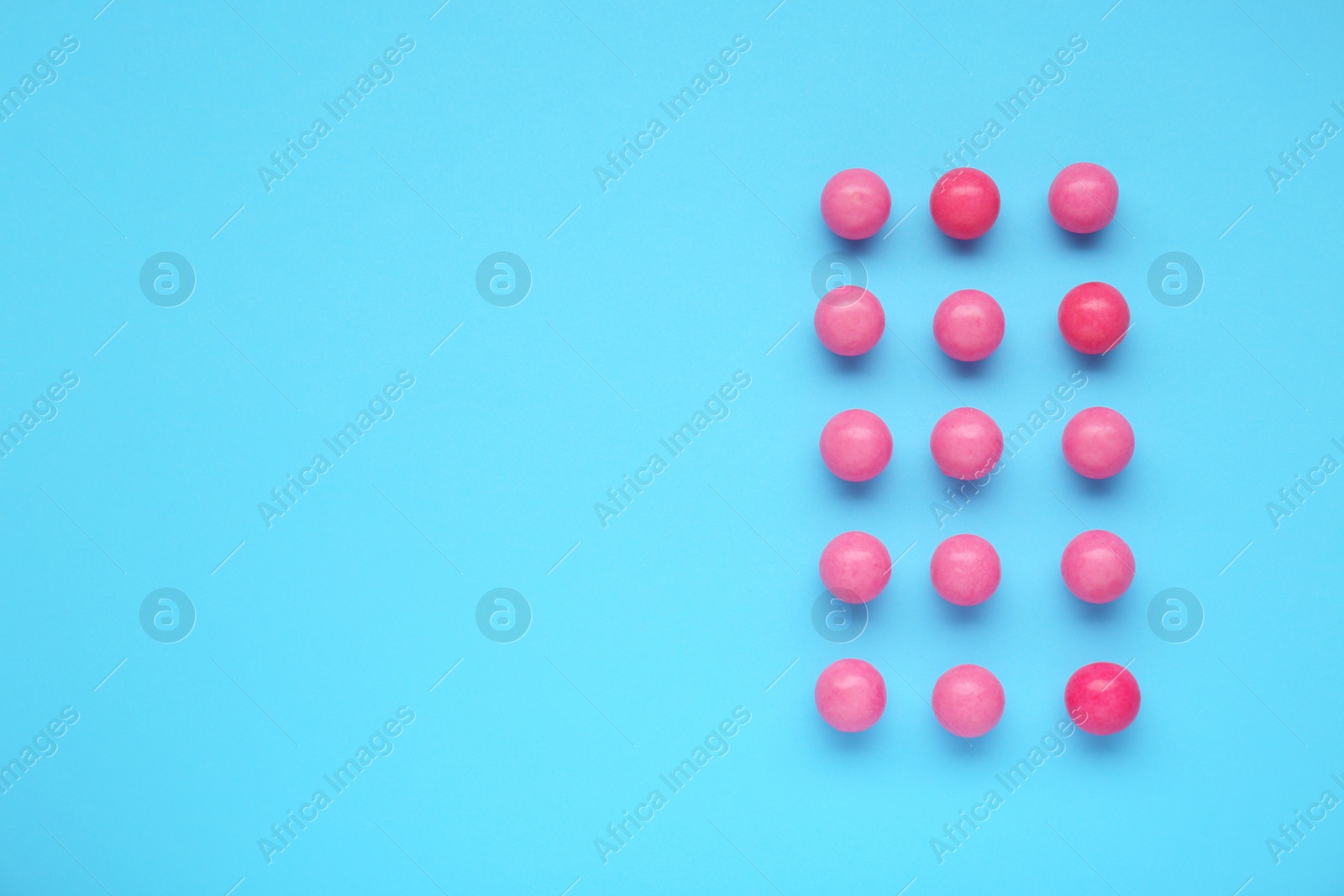 Photo of Many bright pink gumballs on light blue background, flat lay. Space for text