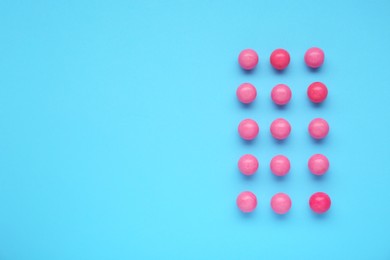 Photo of Many bright pink gumballs on light blue background, flat lay. Space for text