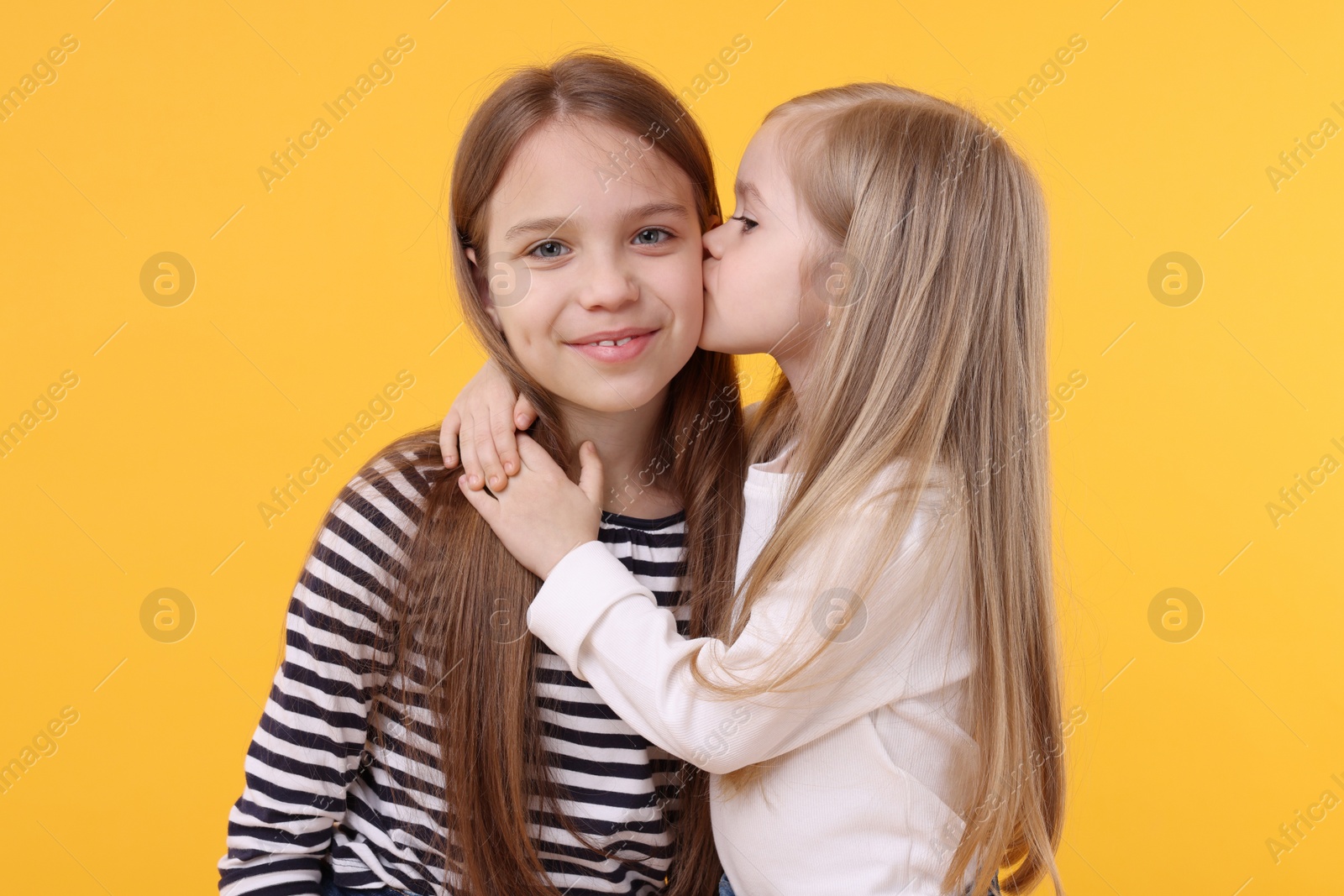 Photo of Portrait of cute little sisters on orange background