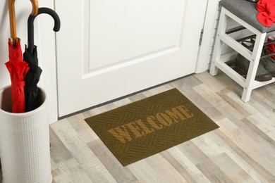 Door mat with word Welcome on wooden floor in hall