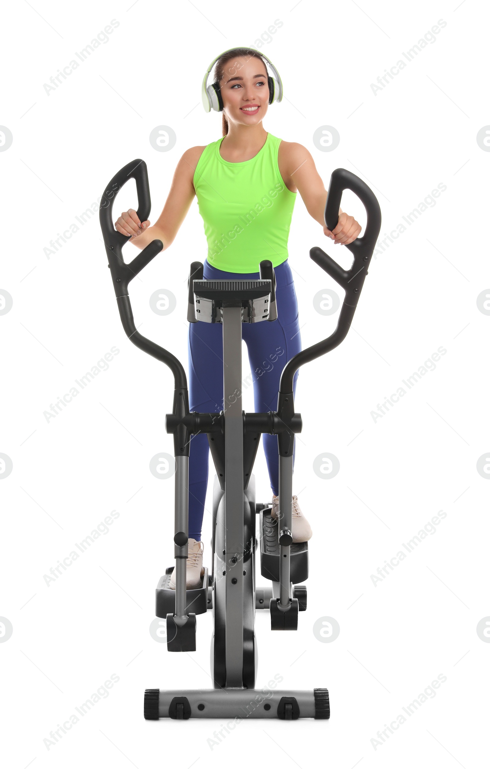 Photo of Woman with headphones using modern elliptical machine on white background