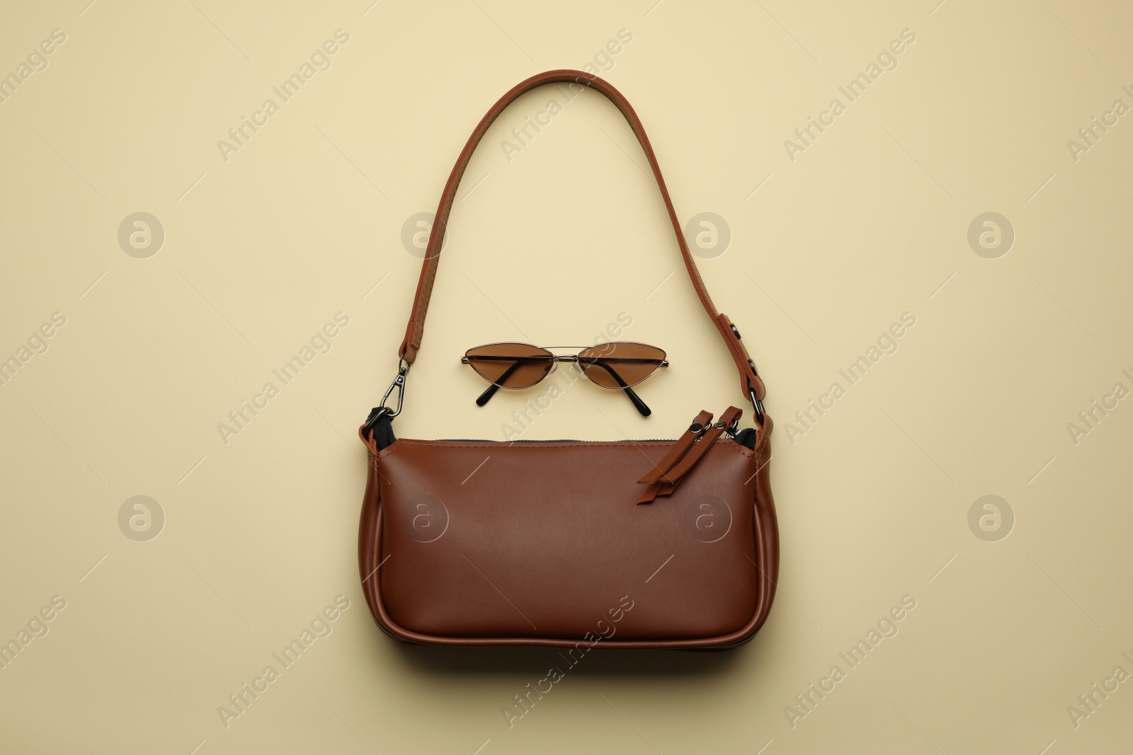 Photo of Stylish woman's bag and sunglasses on beige background, flat lay