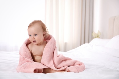 Photo of Cute little baby with soft pink towel on bed after bath. Space for text 