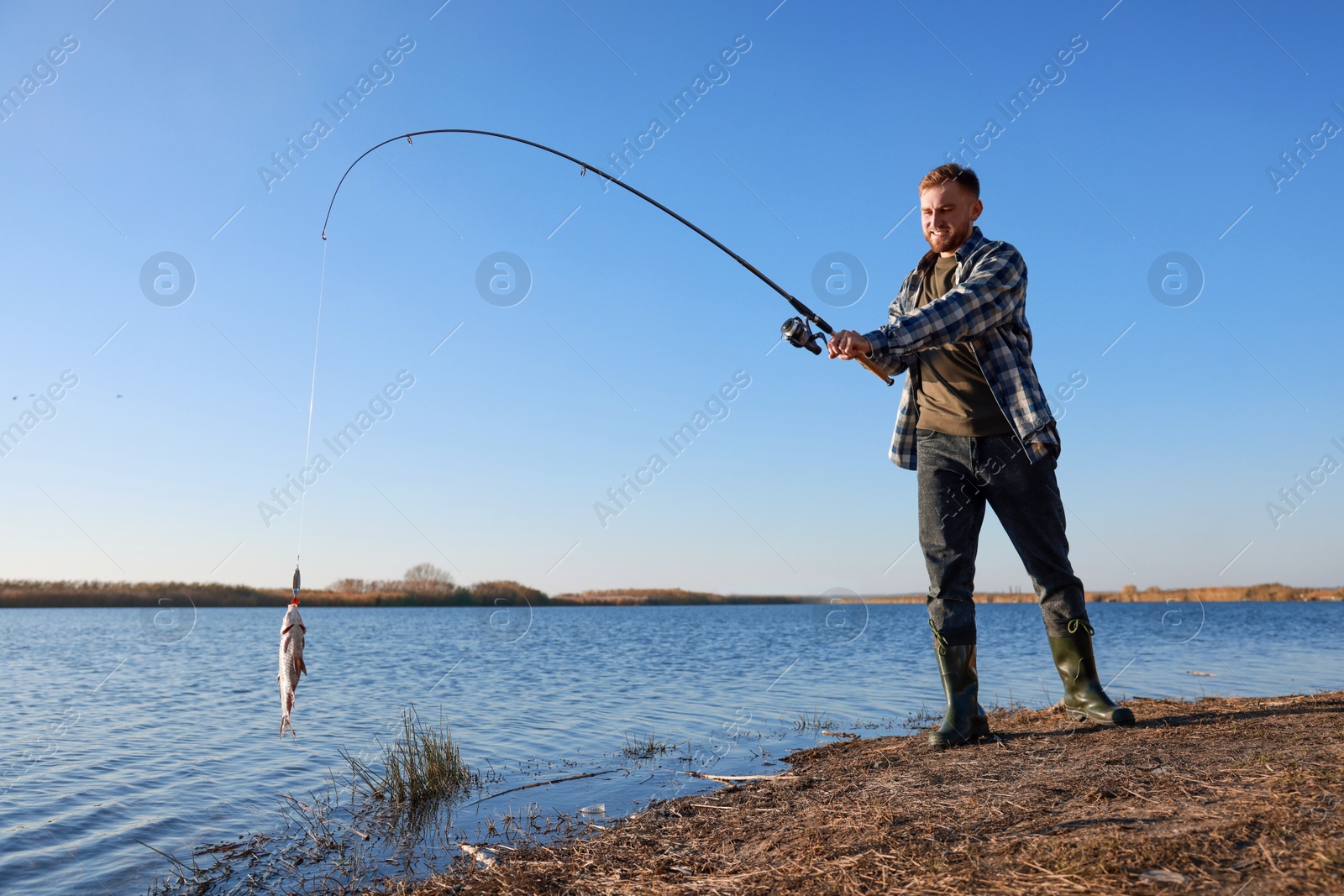 Photo of Fisherman catching fish with rod at riverside