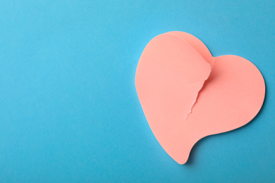 Photo of Torn paper heart on light blue background, top view with space for text. Relationship problems concept