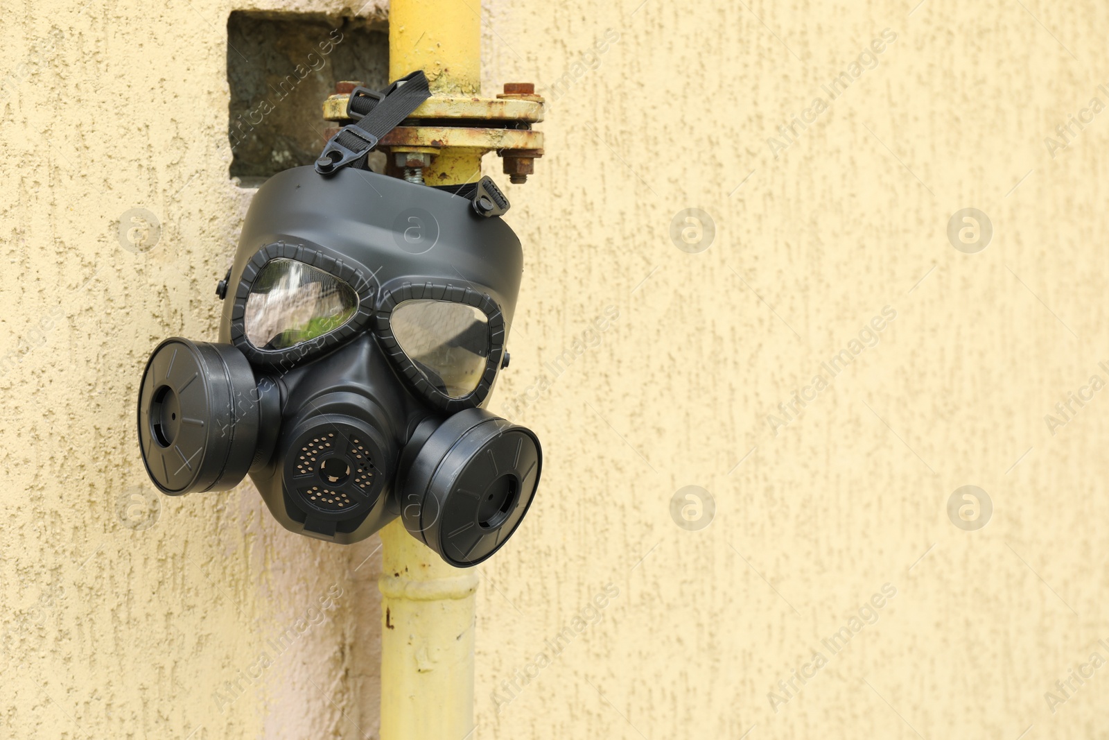 Photo of One gas mask hanging on building outdoors. Space for text