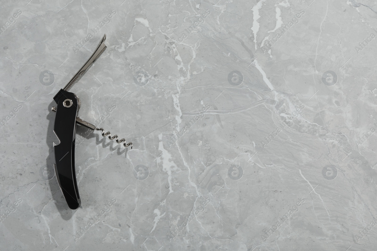 Photo of One corkscrew (sommelier knife) on grey marble table, top view. Space for text