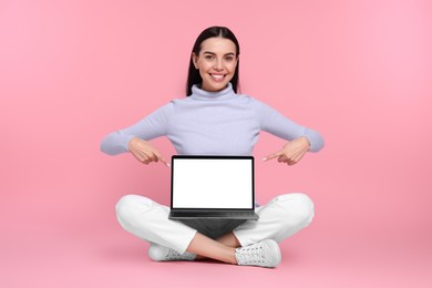 Photo of Happy woman pointing at laptop on pink background