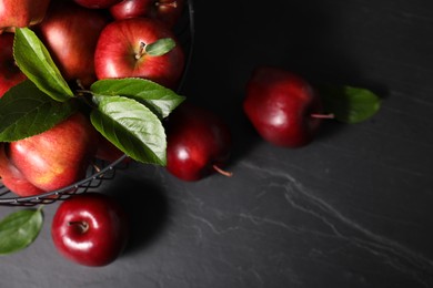 Photo of Fresh red apples and leaves on dark grey table. Space for text