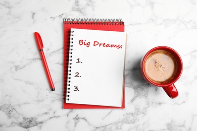 Image of Notebook with dreams list on white marble table, flat lay 