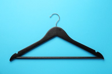Photo of Black hanger on light blue background, top view
