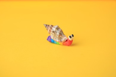 Photo of Snail made from plasticine on yellow background. Children's handmade ideas