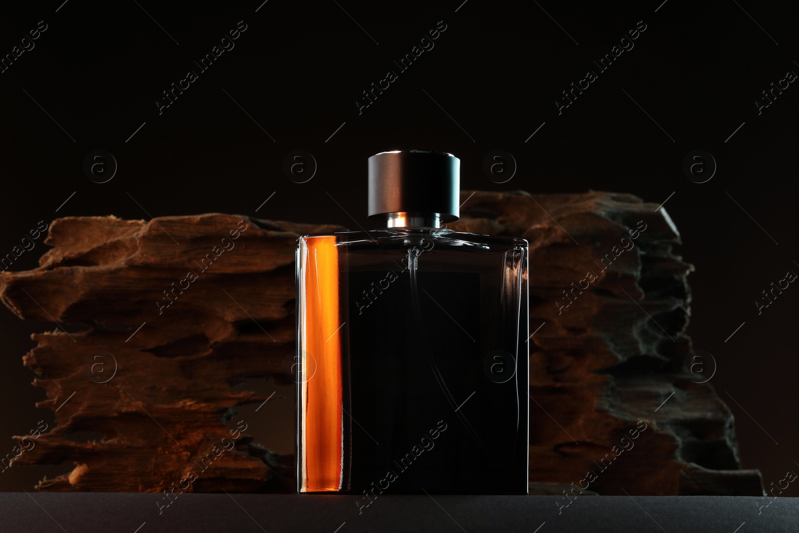 Photo of Luxury men`s perfume in bottle on grey table against dark background