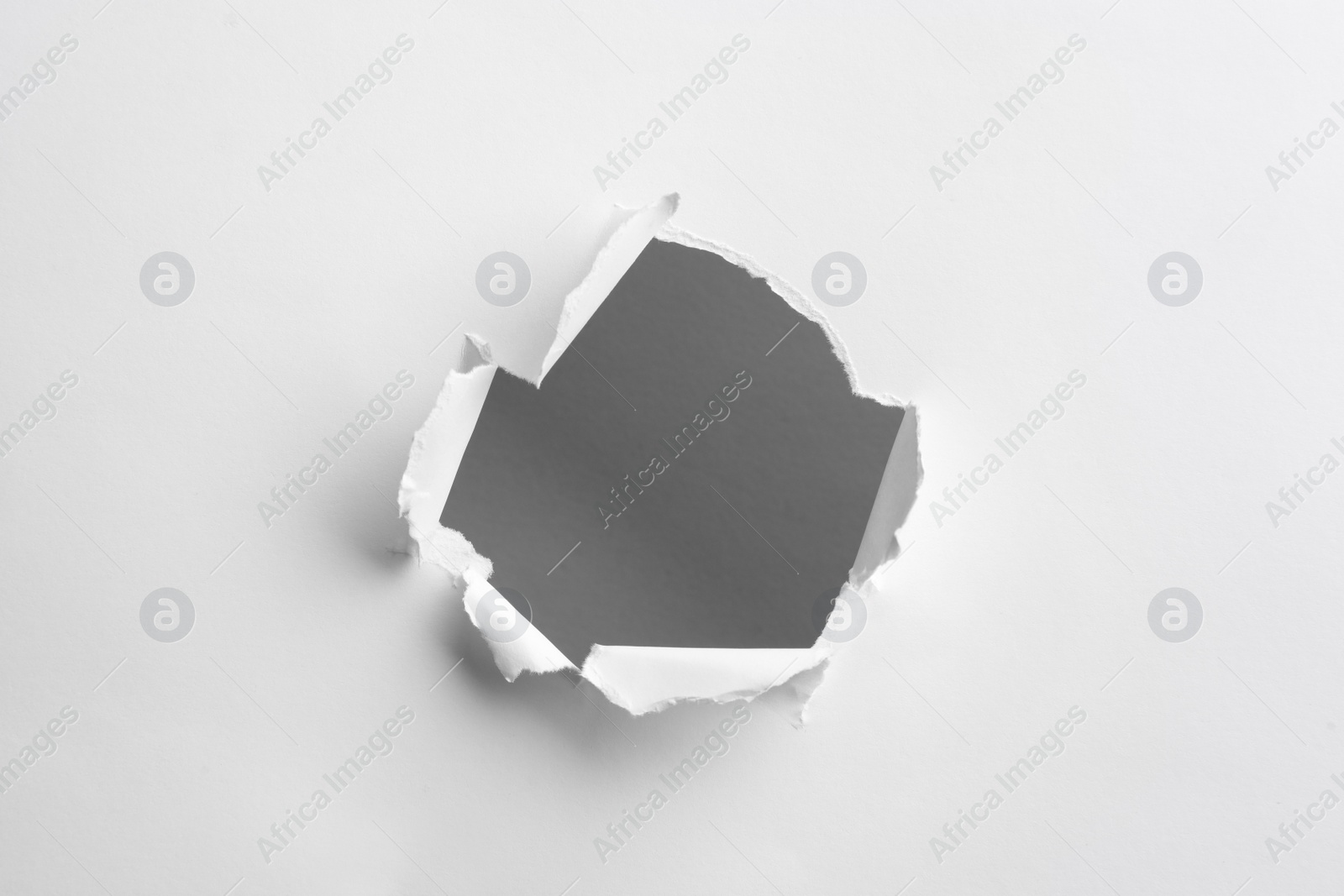Photo of Hole in white paper on light background