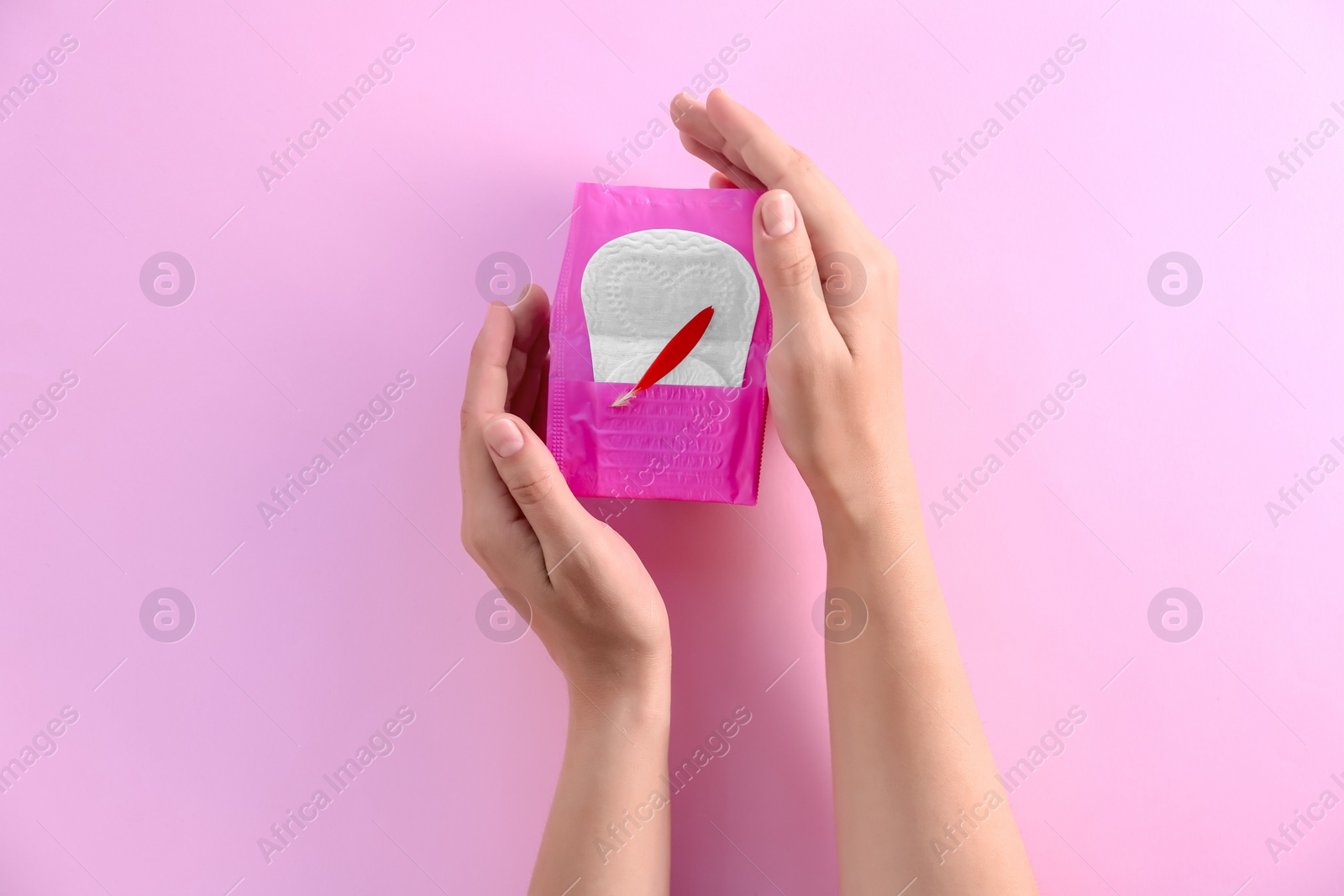 Photo of Woman holding menstrual pad with red flower petal on color background, top view. Gynecological care