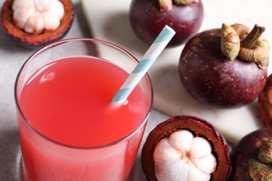 Photo of Delicious mangosteen juice in glass on light table, closeup