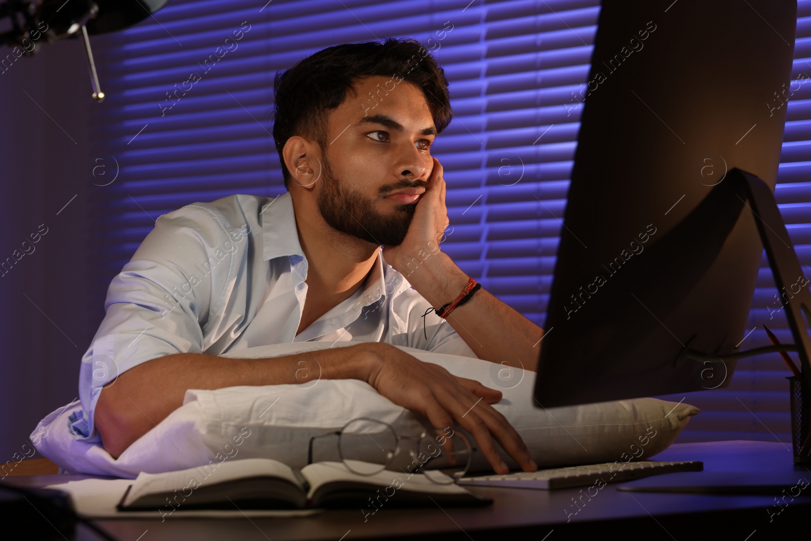 Photo of Tired young man working late in office