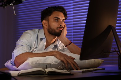 Tired young man working late in office