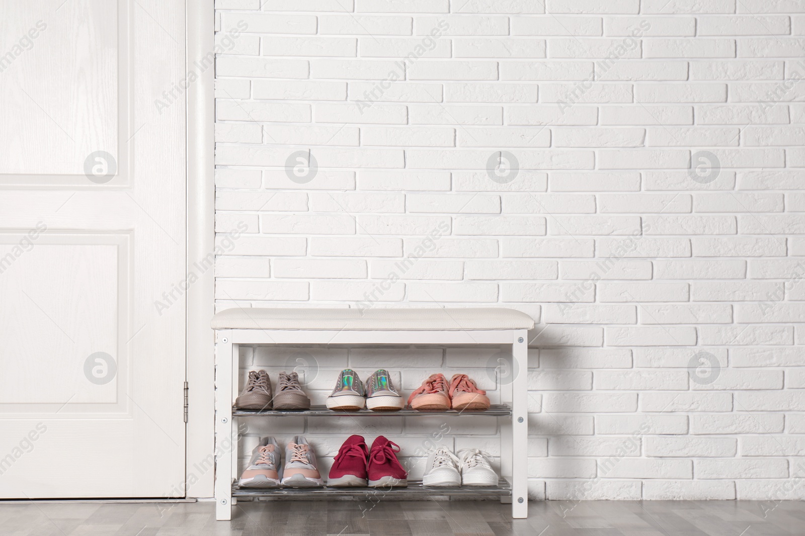 Photo of Shoe storage bench with different sneakers near brick wall, space for text