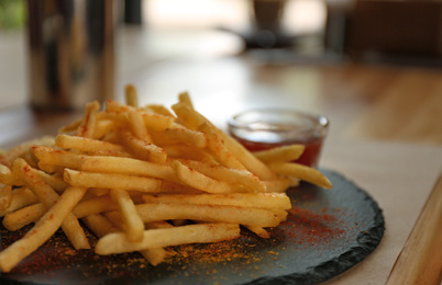 Photo of Delicious hot french fries with red sauce served on table