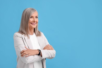 Photo of Portrait of beautiful middle aged woman with crossed arms on light blue background, space for text