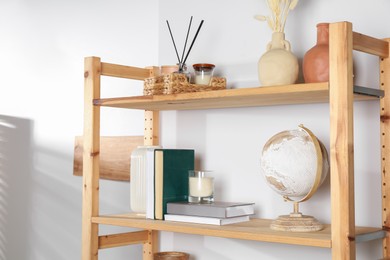 Photo of Wooden shelving unit with home decor near light wall