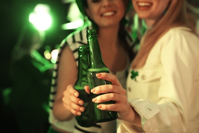 Photo of Women with beer celebrating St Patrick's day in pub, focus on hands