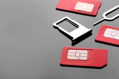 Photo of SIM cards, tray and ejector on grey background. Space for text