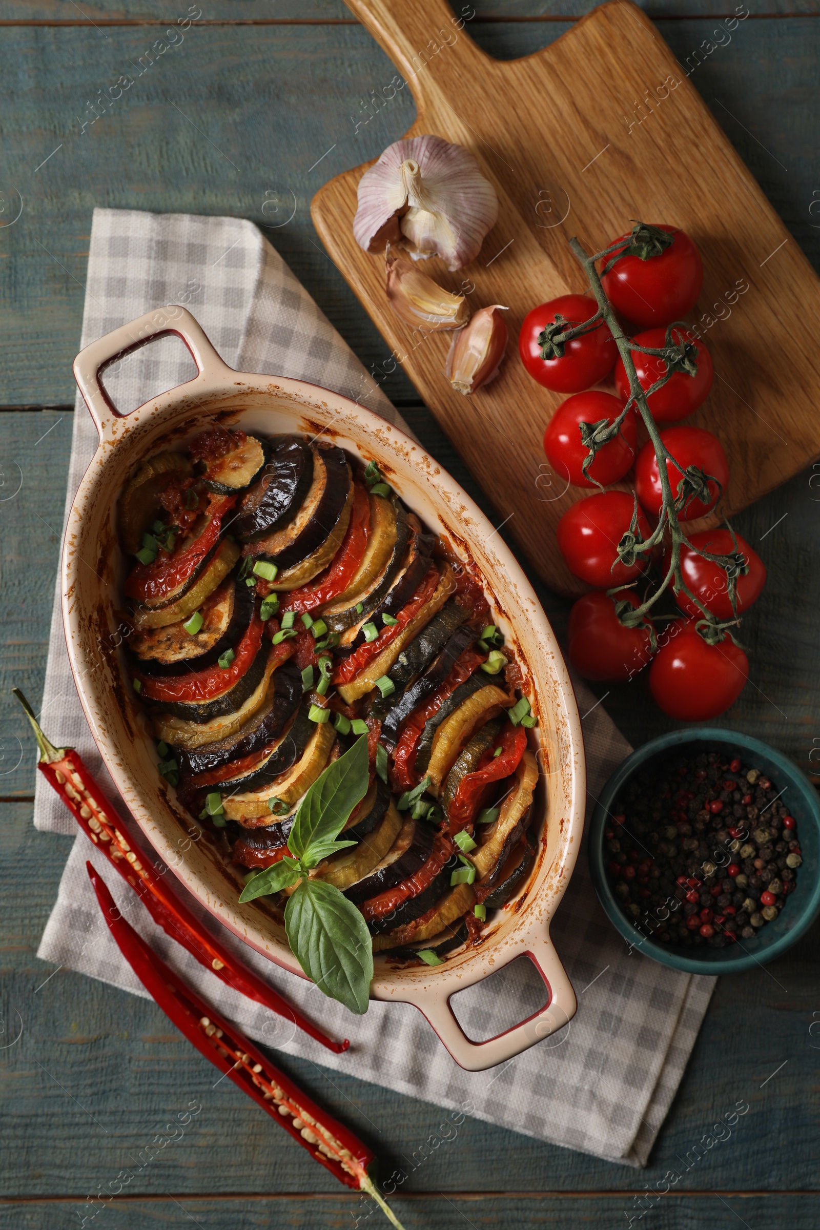 Photo of Delicious ratatouille and ingredients on wooden table, flat lay