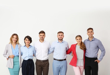 Photo of Group of young people hugging each other on light background. Teamwork concept