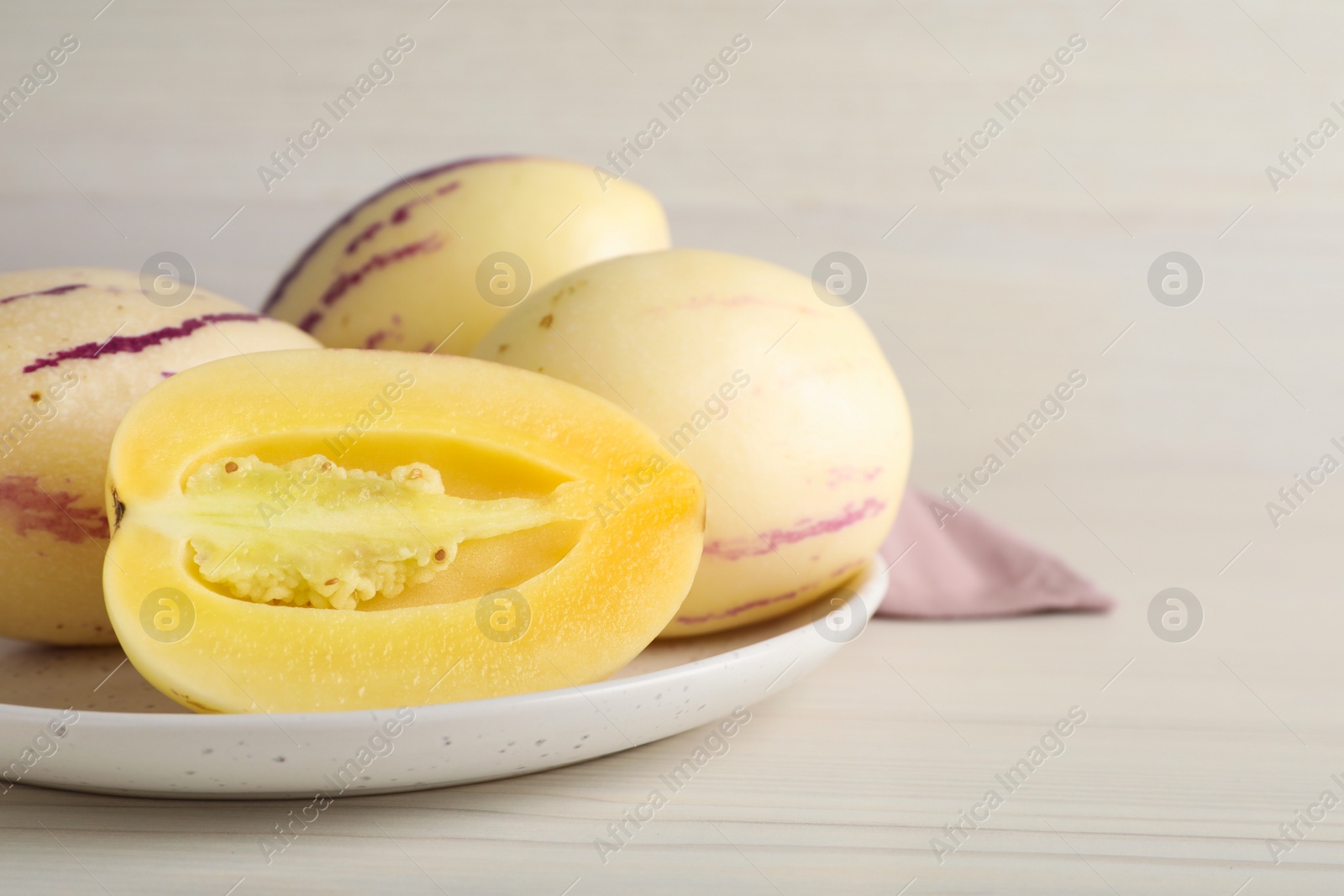 Photo of Fresh ripe pepino melons on white wooden table, closeup. Space for text