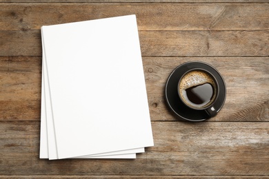 Blank paper sheets for brochure and cup of coffee on wooden background, flat lay. Mock up