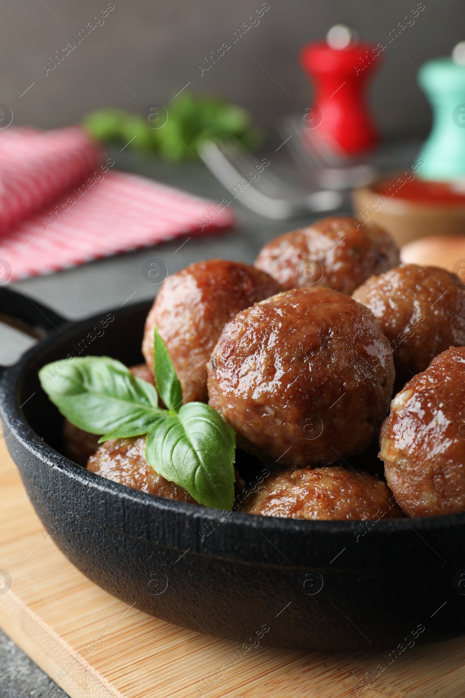 Photo of Tasty cooked meatballs with basil on wooden board, closeup