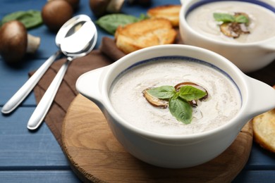 Photo of Fresh homemade mushroom soup served on blue wooden table, closeup