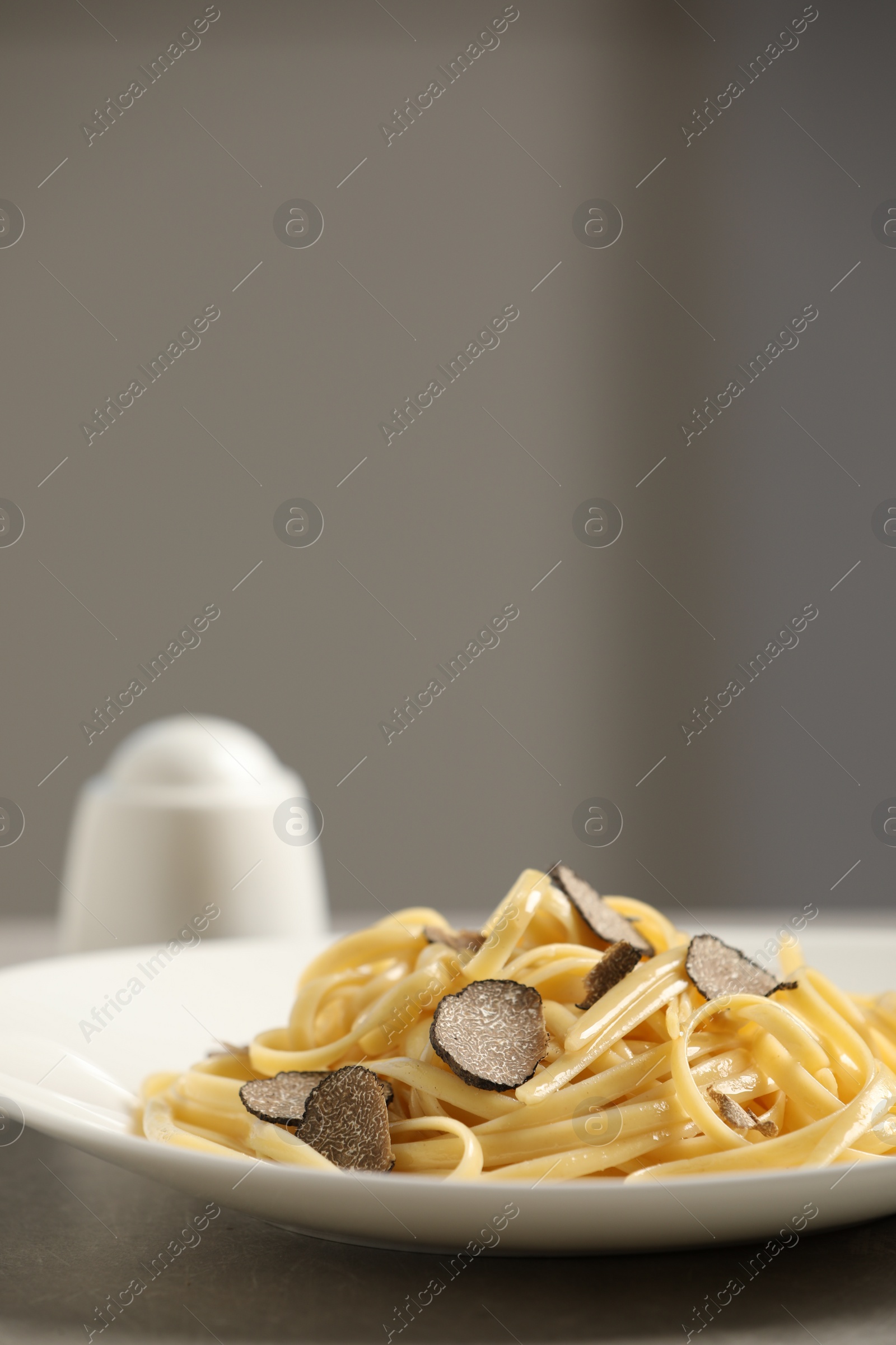 Photo of Tasty fettuccine with truffle on grey table