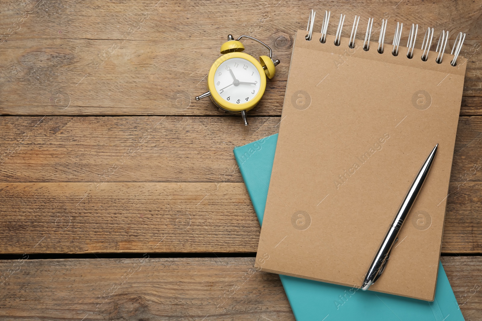 Photo of Notebooks, pen and alarm clock on wooden table, flat lay. Space for text