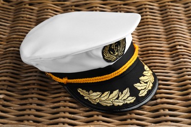 Photo of Peaked cap with accessories on wicker surface, closeup