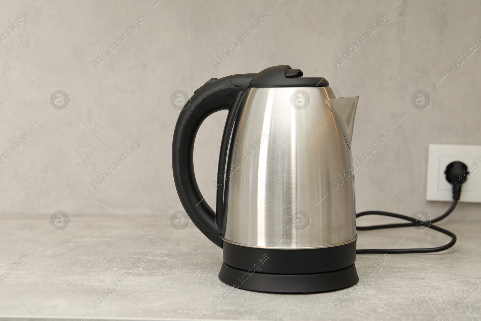 Photo of Modern electric kettle on counter in kitchen. Space for text